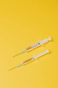 syringes with medical drugs on yellow background